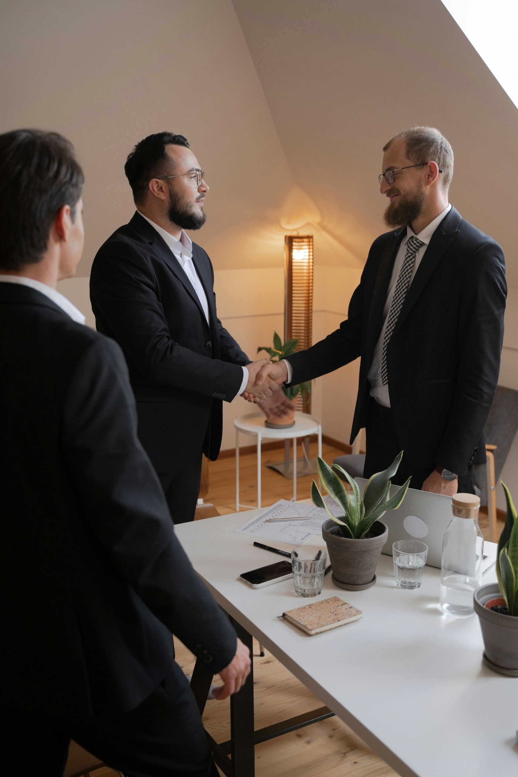 pexels-photo-5520291-5520291 Businessmen in formal attire shaking hands during a meeting in a modern office setting.